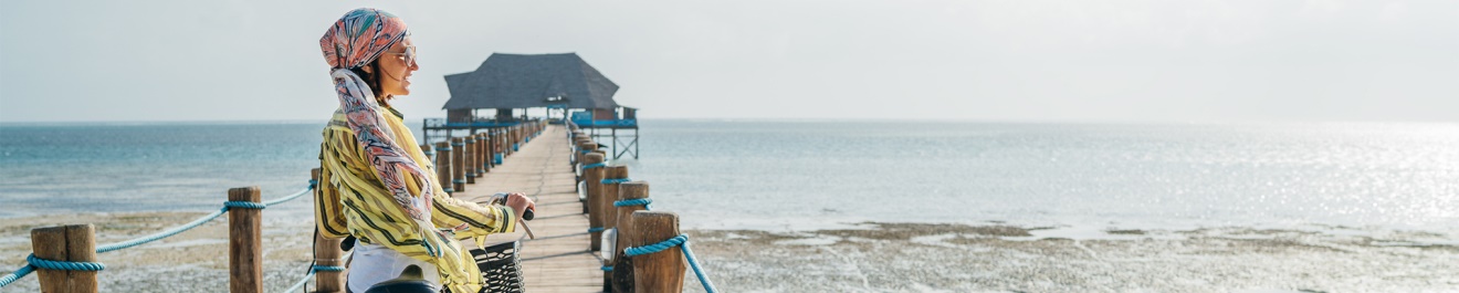 Une femme sur son vélo sur un ponton allant à la mer