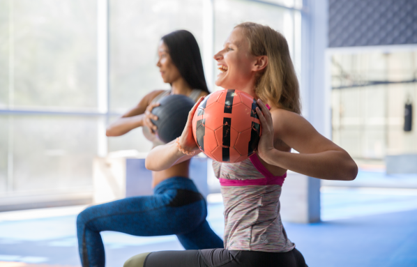 Deux femmes faisant du sport en salle avec un ballon lesté.